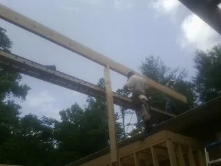 Carpenter setting a ridge beam over a new addition frame — Ice Dam Removal by Roofing Brothers in Balm