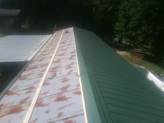 Old rusted panels beside newly installed green metal roofing — Wind Damage Roof Repair by Roofing Brothers in Balm