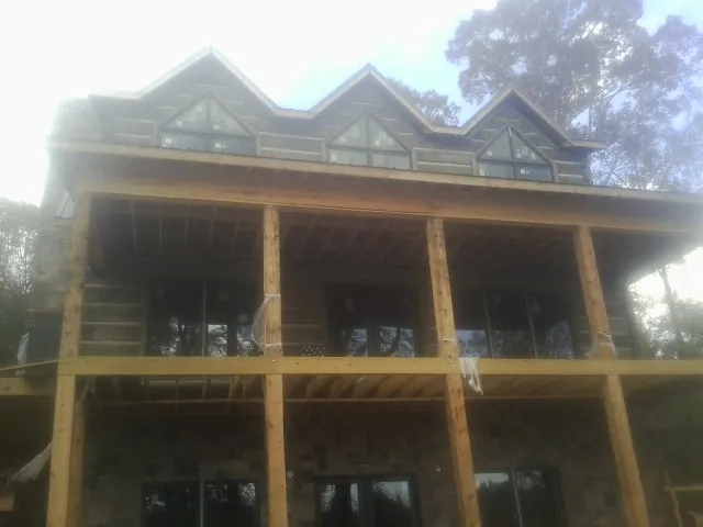 Dormers and porch framing on a large log home under construction — Roof Coating work by our crew in Balm