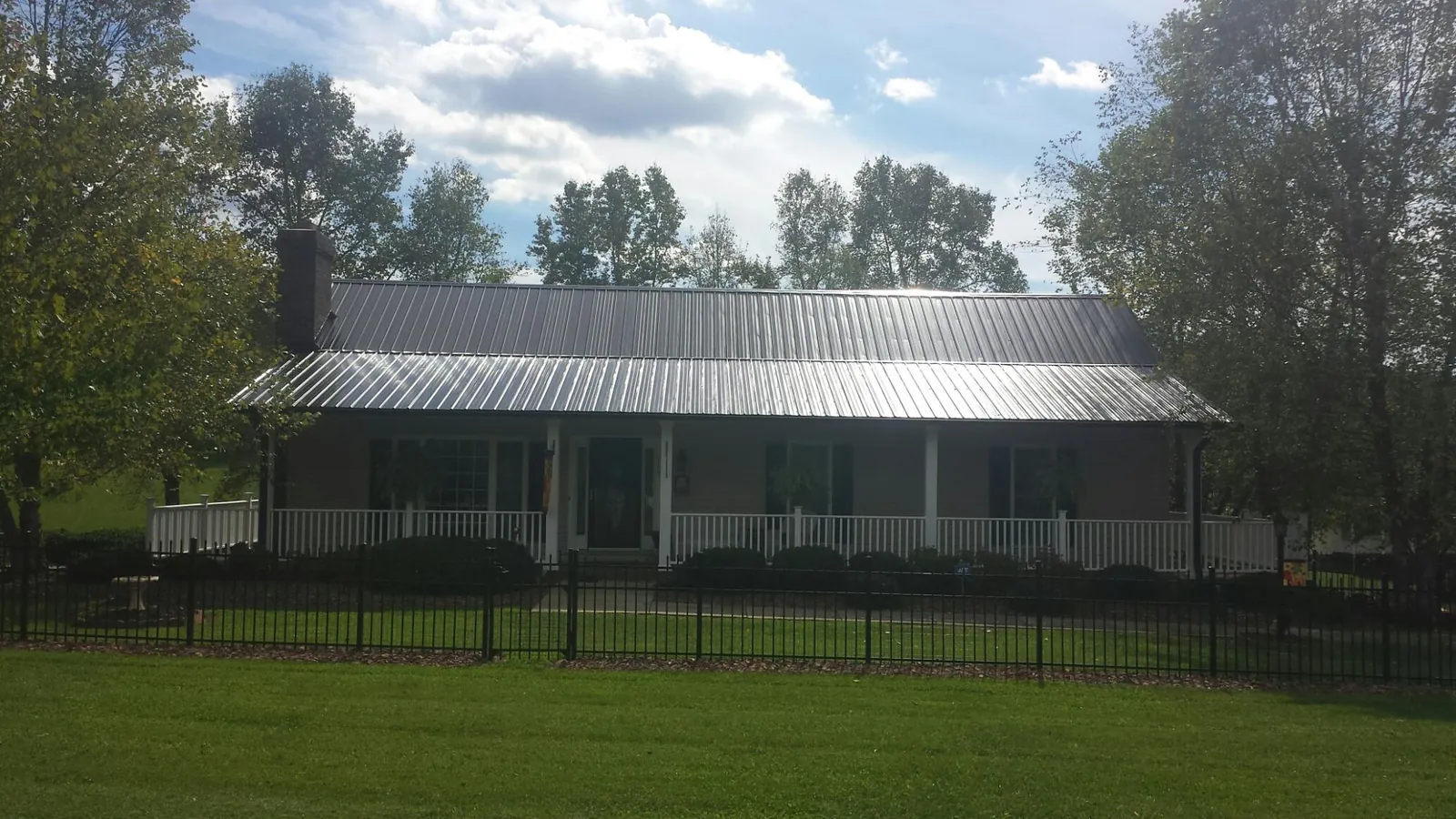 Gray metal roof on a brick ranch with a full width front porch — Gutter Guard Installation work by our crew in Balm