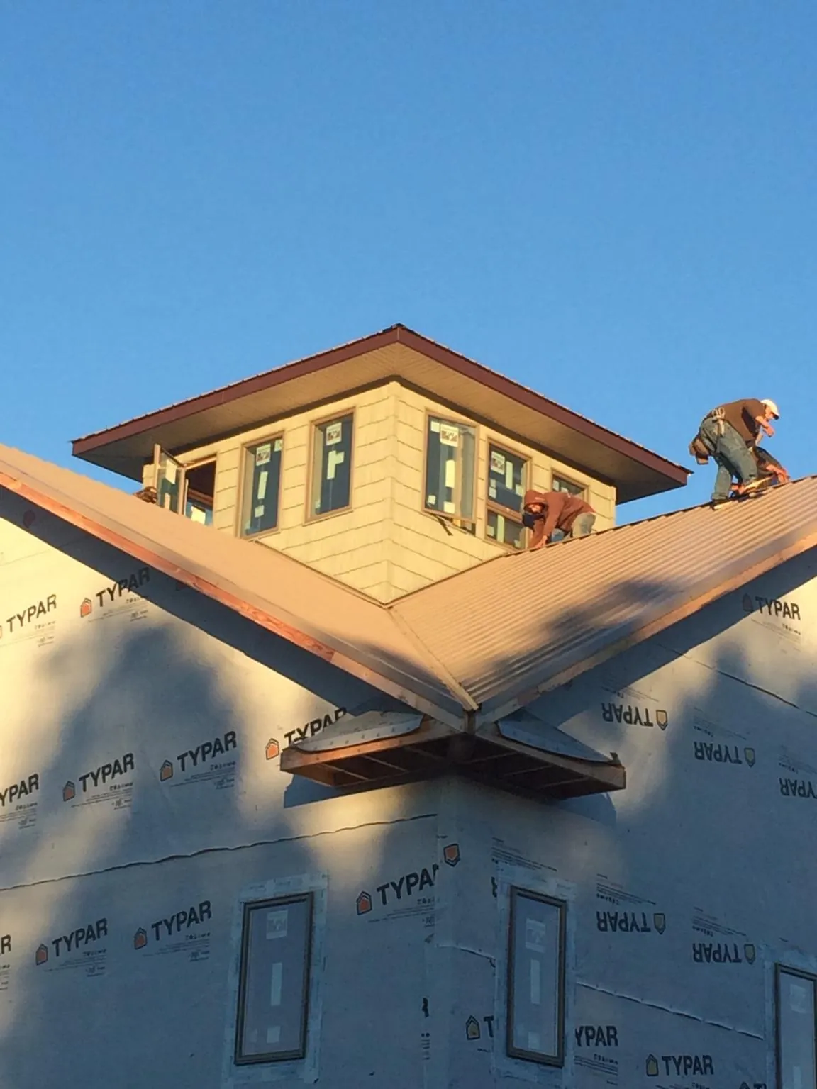 Roofers working around a rooftop cupola on a new metal roof at sunset — Roof Waterproofing in Balm by Roofing Brothers